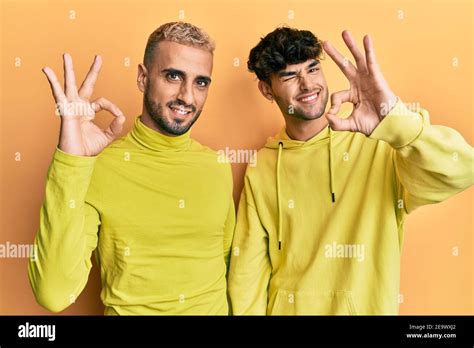 Homosexual Gay Couple Standing Together Wearing Yellow Clothes Smiling Positive Doing Ok Sign