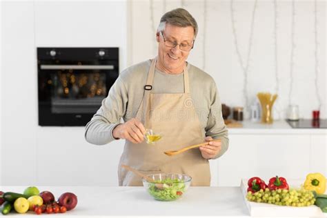 Happy Aged Man Cooking Dinner Standing In Kitchen At Home Stock Photo