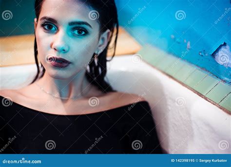 Girl With Bare Shoulders Lying In The Bathroom With Colored Purple Water Fashion Concept Stock