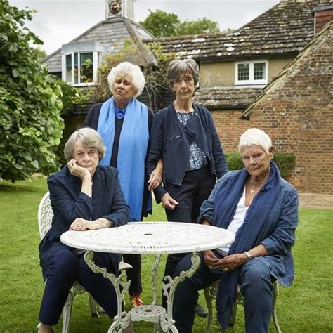 Four Women Sitting At A Table Outside In The Grass