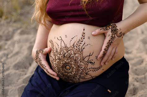 Pregnant belly with mehendi henna tattoo on the beach, cropped image ...