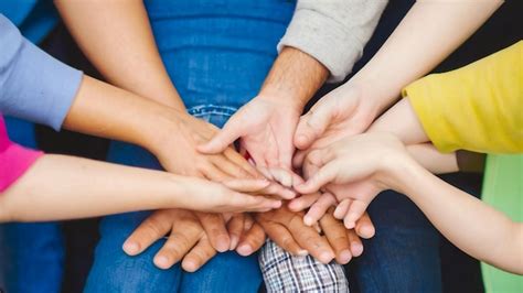 Un Grupo De Personas Con Las Manos Juntas Una De Las Cuales Sostiene