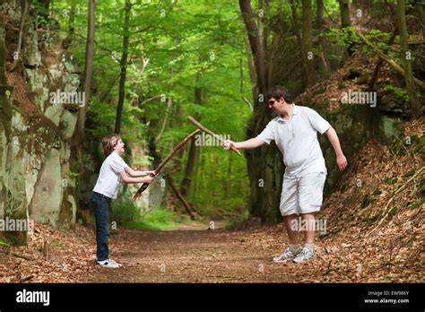 Father And Son Playing With Sticks On A Hike In A Beautiful Nature Park