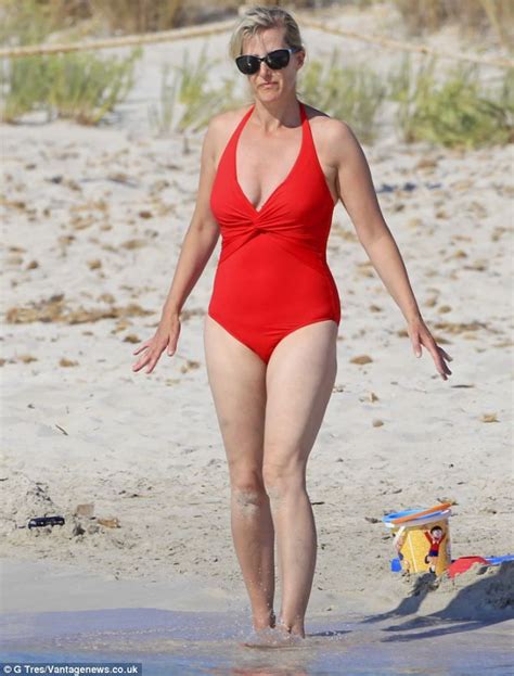 A Woman In A Red Swimsuit Walking On The Beach