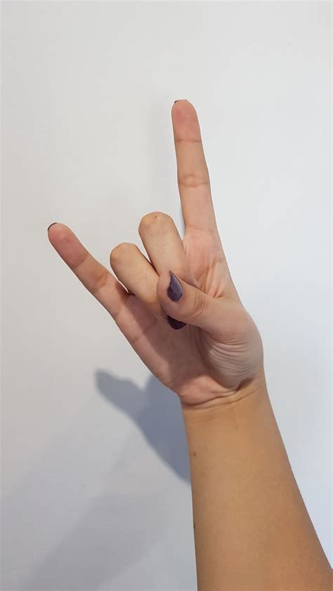 A Person S Hand Making The V Sign With Their Fingers Against A White