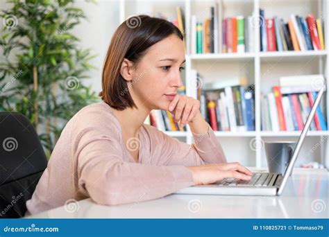 Girl Sitting At The Desk In Front Of Personal Computer Stock Image