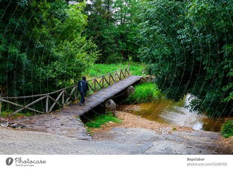 Pilgrim Walking On The Wooden Bridge Over The River Along The Camino De