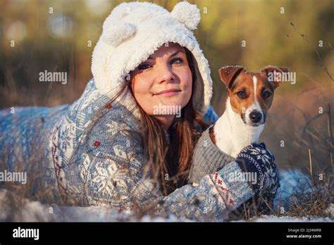 Young Woman In Winter Jacket Lying Down At Snow Covered Ground Holding