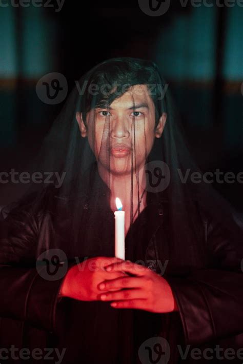 A Man Dressed All In Black Holding A Candle When Going To A Cemetery To