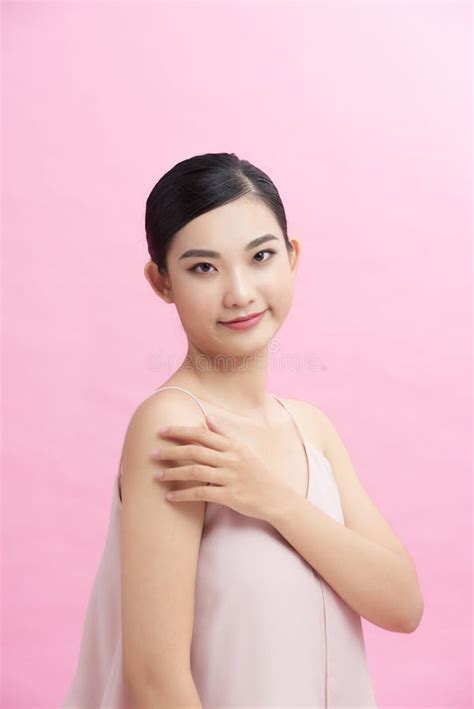 Asian Girl With Perfect Glowing Skin And Nude Natural Makeup Posing Against Pink Background