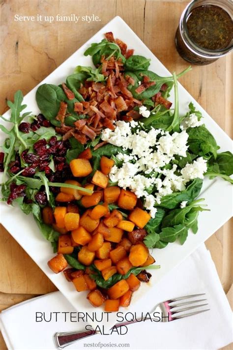 A White Plate Topped With Butternut Squash And Spinach Salad