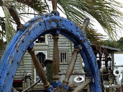 An Old Painted Ships Wheel Is Displayed In Front Of A Seaside Cottage