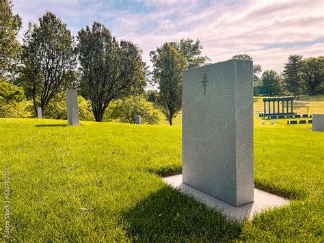 Focus on a single empty tombstone in a row of unmarked gravesites. The ...