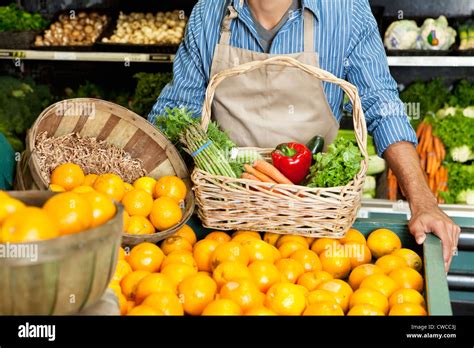 Midsection of man standing near oranges stall with vegetable basket in ... 
