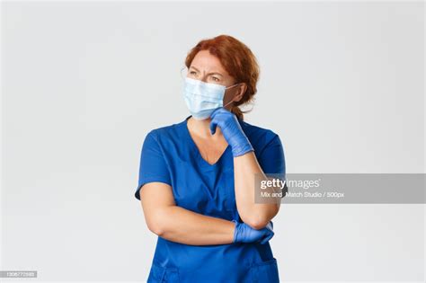 Portrait Of Female Doctor Wearing Surgical Mask Against White