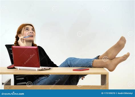 Happy Young Office Worker Woman Sitting Relaxed With Feet On Table Behind Working Desk With