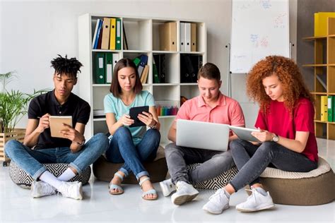 Amigos Multirraciales Que Estudian Con Aparatos Electr Nicos Y Libros