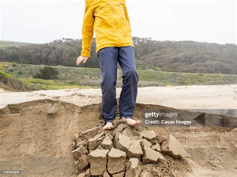 Detail Of Young Person Standing On Crumbling Edge Of Sandy Ledge High