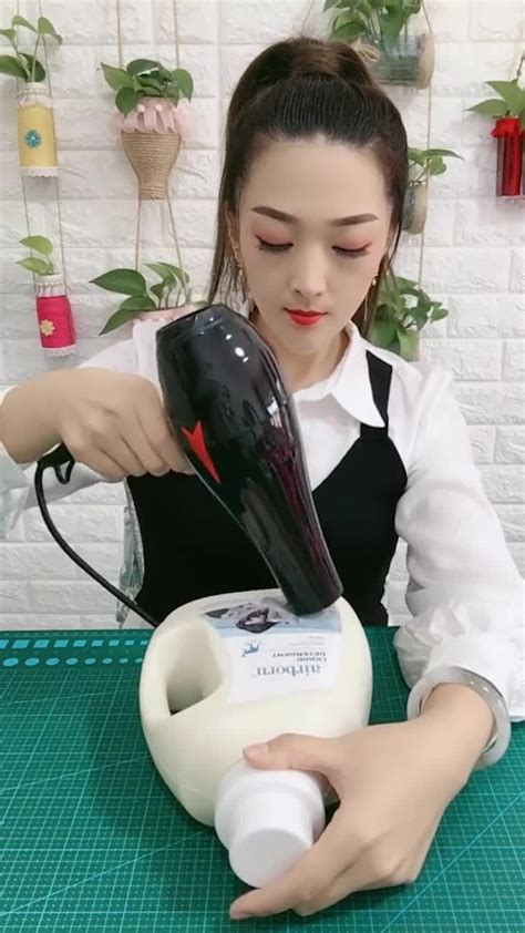 A Woman Using A Hair Dryer On Top Of A Table