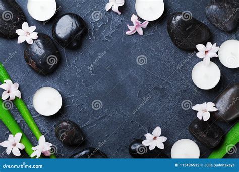 Spa Background With Massage Pebble Green Leaves Flowers And Candles On Black Stone Table Top