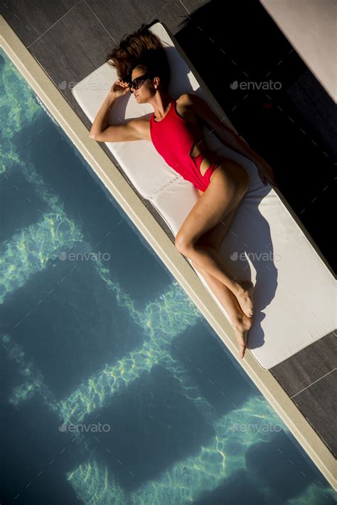 Beautiful Tanned Woman In Red Bikini Relaxing Near Luxury Swimming Pool