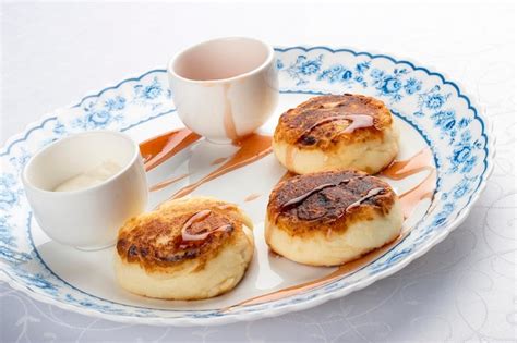 Panqueques De Cuajada Con Crema Agria Y Mermelada En Un Plato Blanco