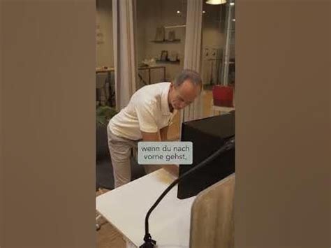 An Old Man Standing Over A Table With A Lamp On It S Head And Looking