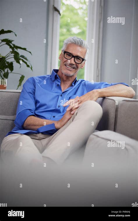 Portrait Of Smiling Mature Man Sitting On Couch At Home Stock Photo Alamy