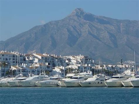 Many Boats Are Docked In The Water Near Some Buildings With Mountains