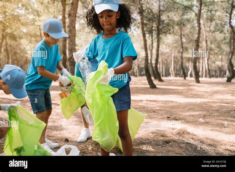 Group Of Volunteering Children Collecting Garbage In A Park Stock Photo