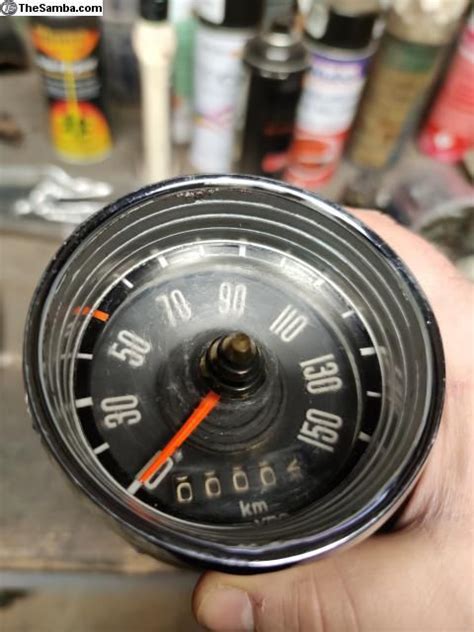 A Man Is Holding An Old Clock In His Left Hand With Other Tools Behind Him