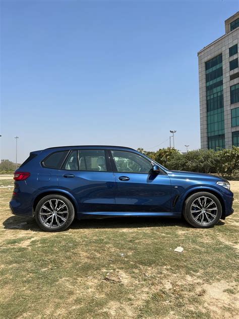 A Blue Bmw X Parked In Front Of A Tall Building On A Sunny Day