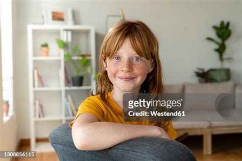 Smiling Redhead Girl With Blue Eyes Sitting On Chair At Home High Res