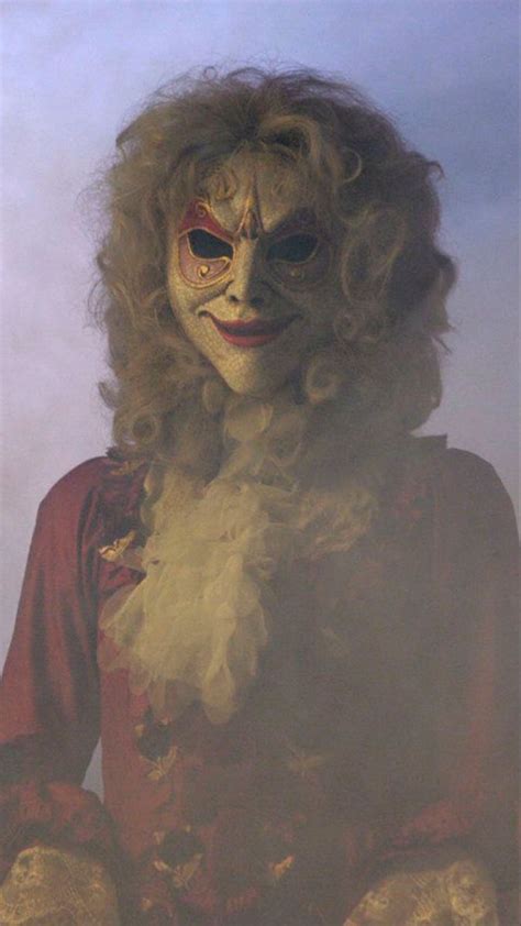 a man with long blonde hair wearing a creepy mask and holding something ...