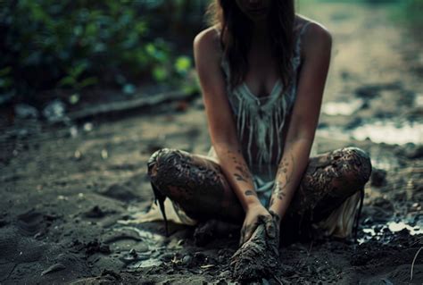 Premium Photo | A girl with a tattoo on her arm sits in the mud