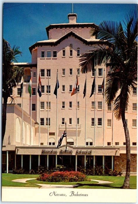 A Large White Building With Palm Trees And Flags On The Front Lawn In