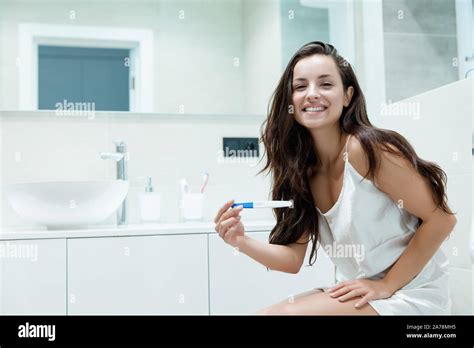 Young Beautiful Woman Sits On The Toilet Bowl Holding