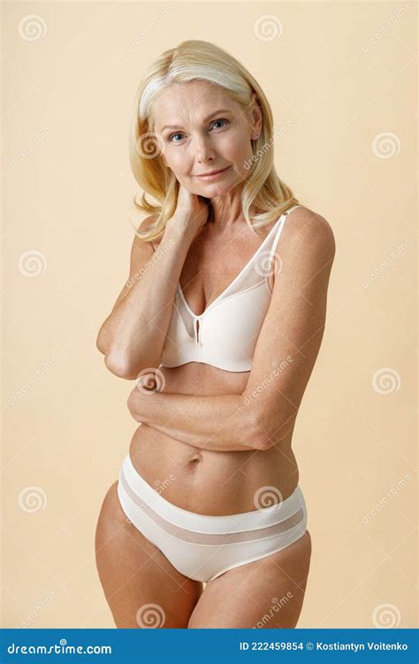 Studio Shot Of Attractive Mature Woman With Blonde Hair In White