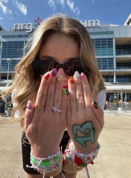 A Woman With Her Hands In Front Of Her Face Covered By Tattoos And Bracelets