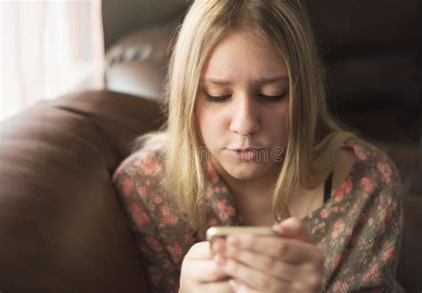 Menina Adolescente Que Senta Se Na Cadeira E Que Olha O Telefone Foto