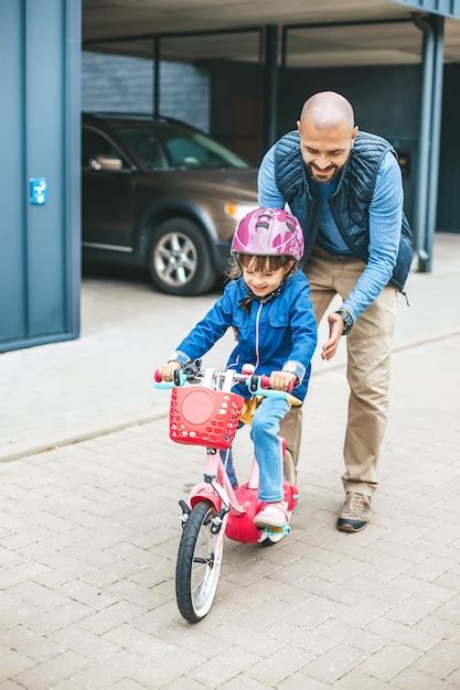 Una niña feliz montando en bicicleta con su padre ayuda padre enseñando