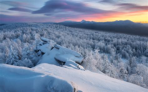 Kolorowe niebo nad górami i zaśnieżonym lasem