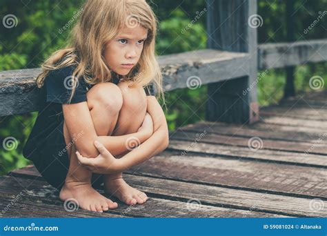 Portrait De La Petite Fille Blonde Triste Sasseyant Sur Le Pont Photo