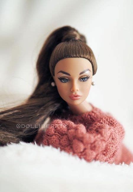 A Close Up Of A Doll With Long Hair Wearing A Pink Sweater And Pearl