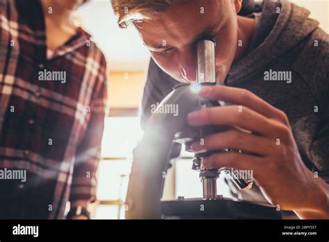 High School Student Using A Microscope In A Science Class Boy Looking