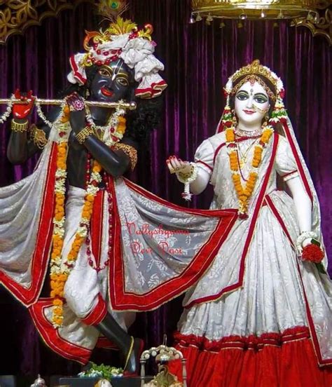 a statue of the hindu god and goddess in front of a purple curtained stage