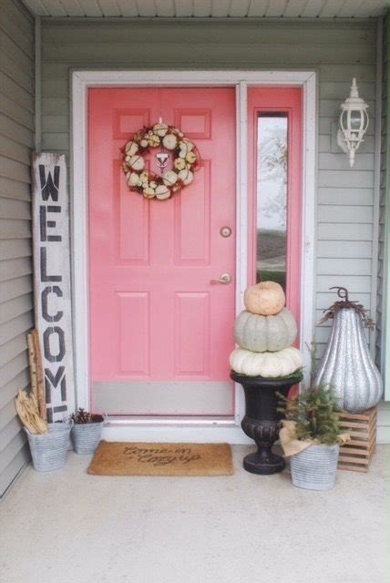 A Pink Front Door With Pumpkins And Other Decorations