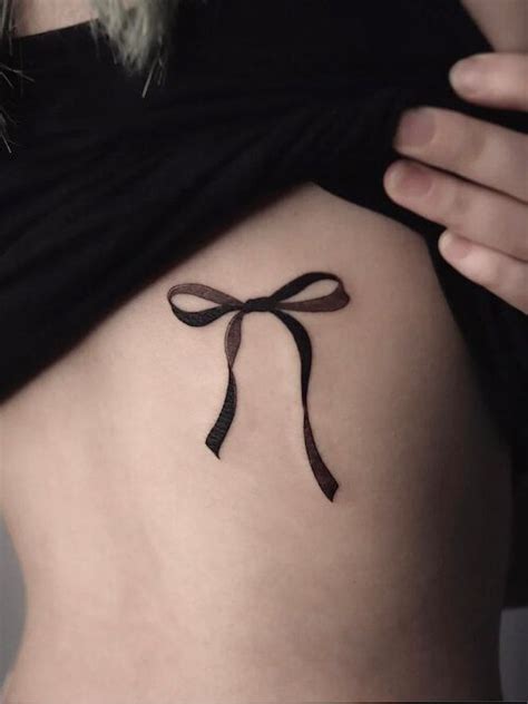 A Woman With A Tattoo On Her Stomach That Has A Bow At The Top And Bottom