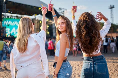 Back View Three Girls Enjoy Music Fest On Sandy Beach Hold Colorful