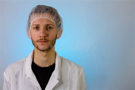 An Adult Male Dressed In A White Lab Coat With A Hair Net On Ready To